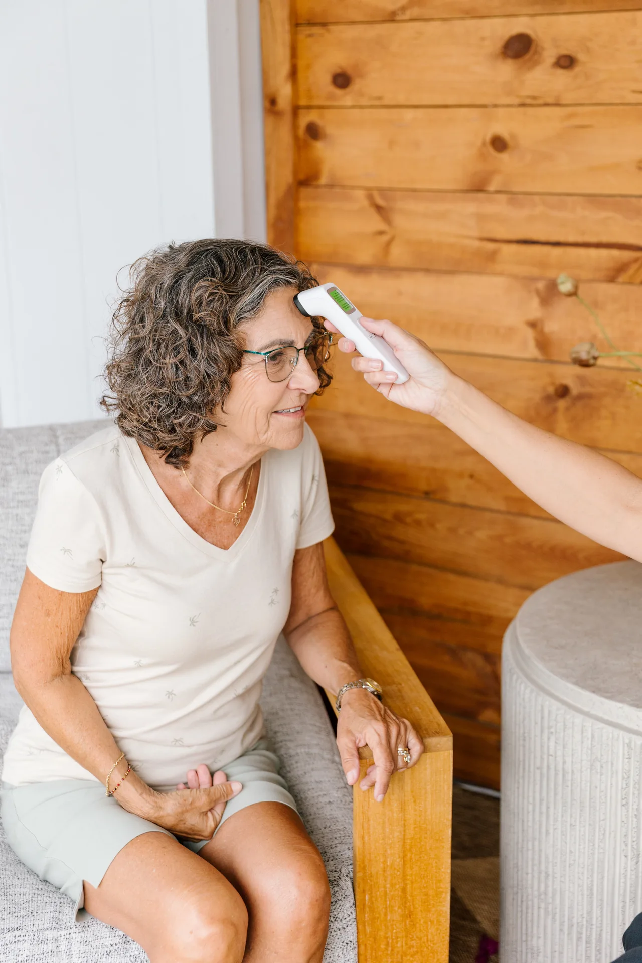 A Prata Health nurse checking an older woman's temperature during an in-home visit