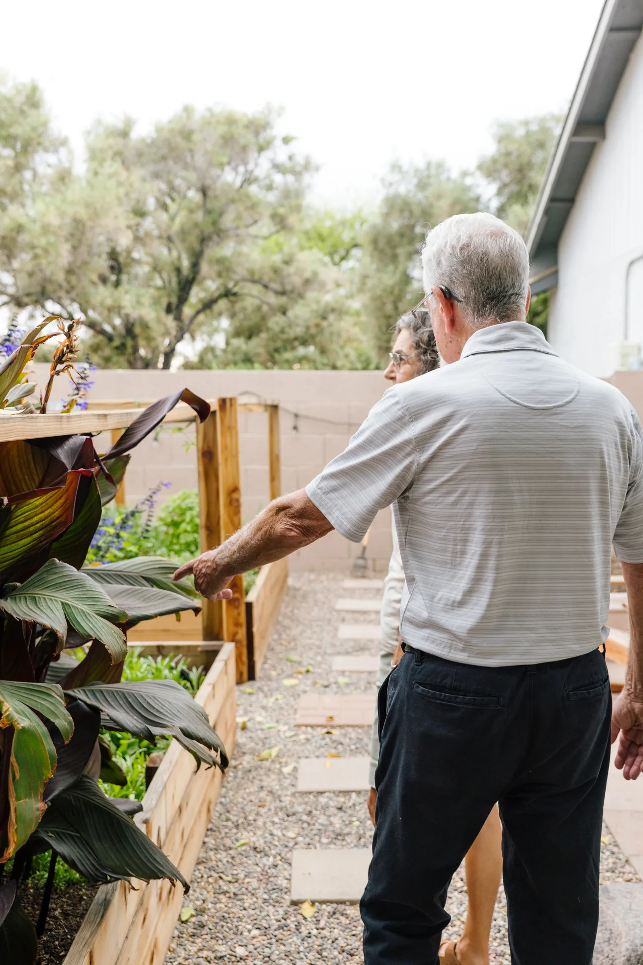 An older couple tending a raised garden bed together at home