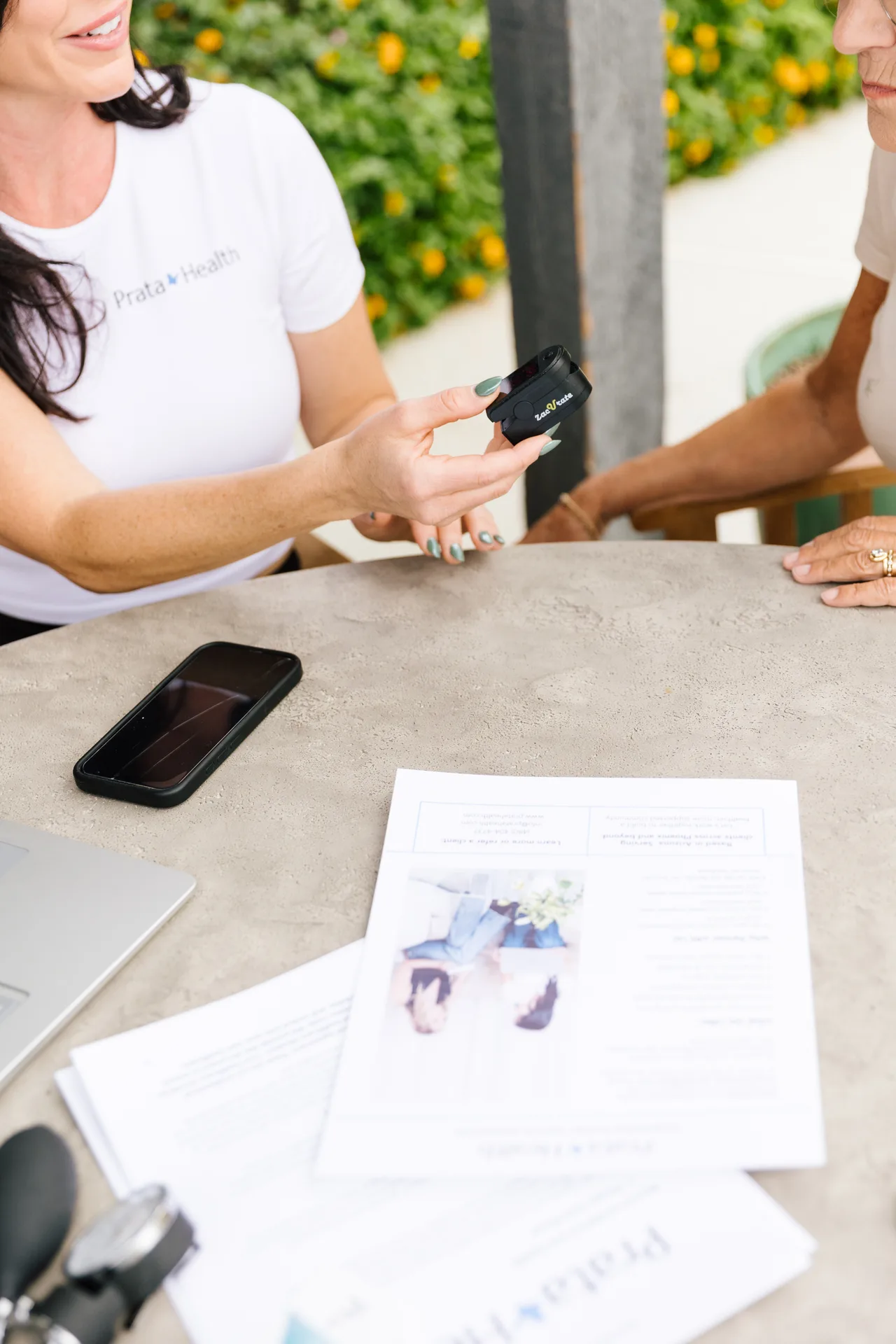 A registered nurse reviewing care documents and readings with a client at a table