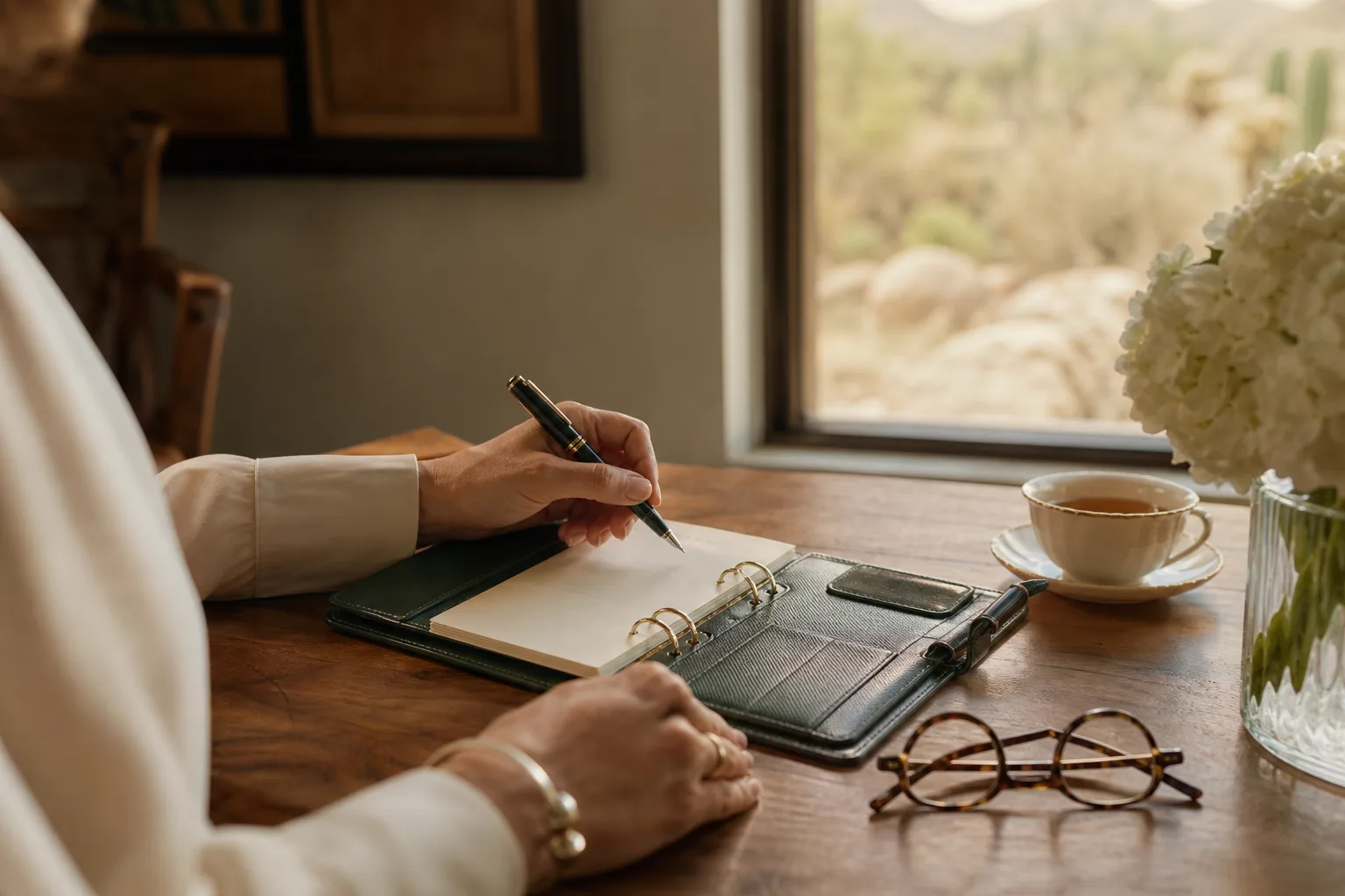 A leather folio, pen, and tea on a sunlit table, representing care coordination